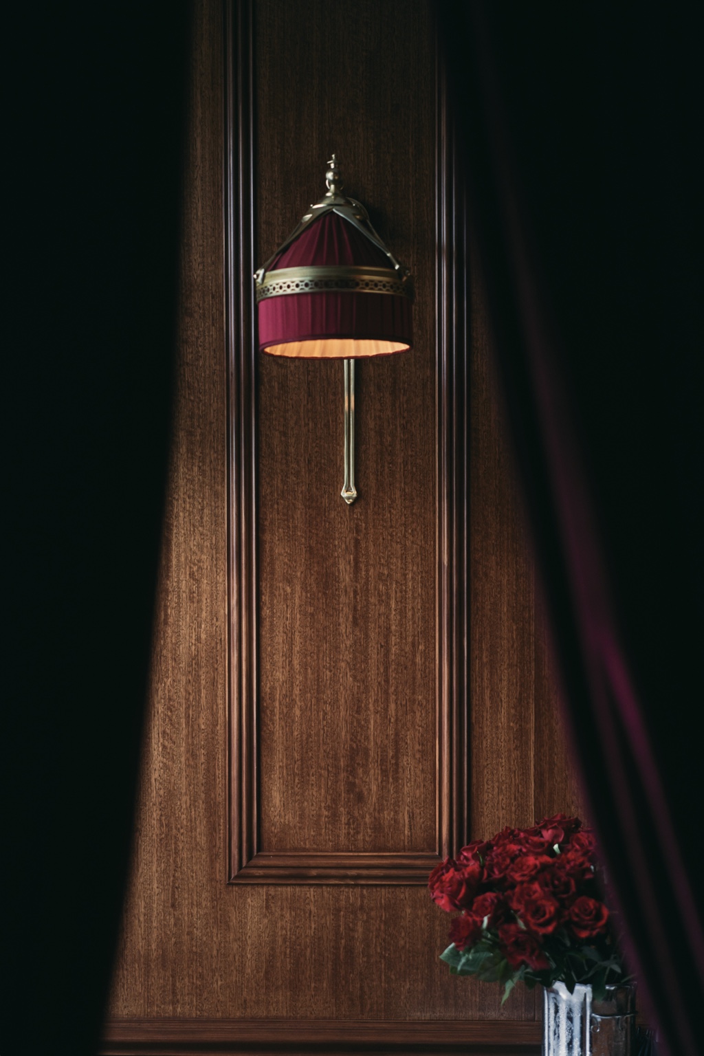 A burgundy wall lamp and roses at Le Splendide